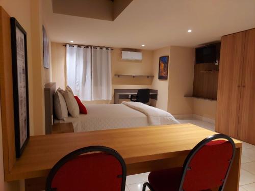 a bedroom with a bed and a desk and chairs at Hotel Vila Suíça 1818 in Nova Friburgo