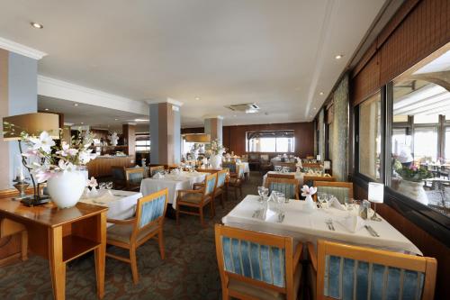 a restaurant with white tables and chairs and flowers at Van der Valk Hotel Saint-Aygulf in Saint-Aygulf