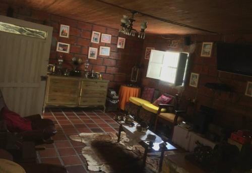 uma sala de estar com um sofá e uma televisão e uma parede de tijolos em Acogedora casa de campo en el oriente de Antioquia em El Retiro