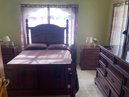 een slaapkamer met een groot houten bed en een dressoir bij PearlieRon Place in Runaway Bay