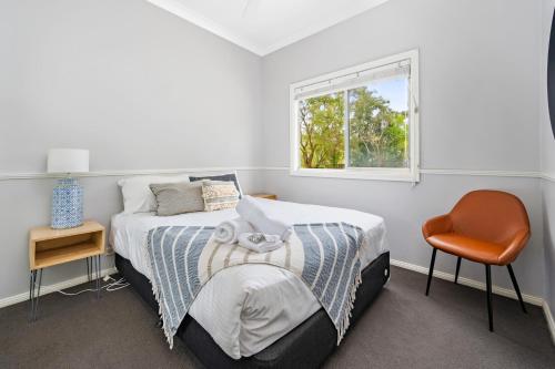 um quarto com uma cama, uma cadeira e uma janela em Koala Shores Holiday Park em Lemon Tree Passage