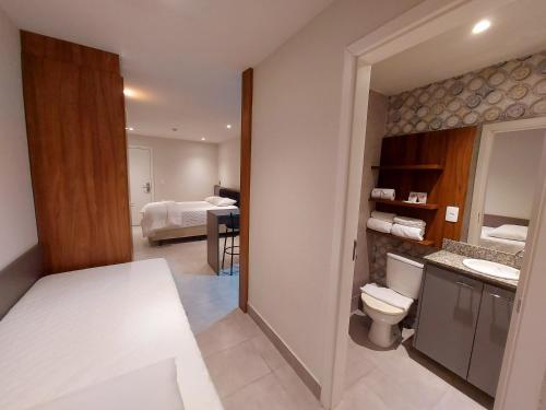 Hotel Vila Suíça 1818 في نوفا فريبورغو: حمام مع مرحاض وغرفة نوم مع سرير