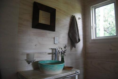 baño con lavabo azul y ventana en Hermosa cabaña en la naturaleza. Chacra La Fiaca, en Colonia del Sacramento