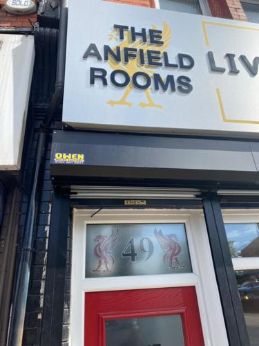 um sinal acima de uma porta vermelha de um edifício em The Anfield Rooms em Liverpool