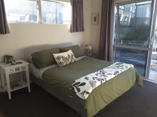 a bed in a room with a window and a bed sidx sidx sidx at Mangawhai Modern in Mangawhai