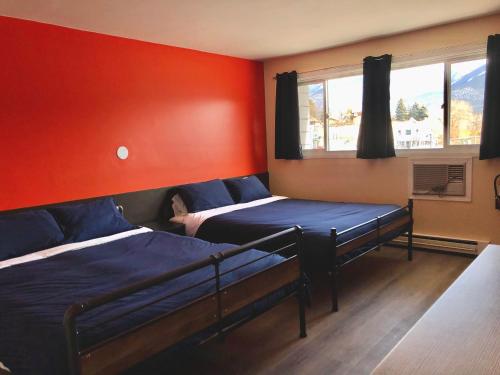 1 Schlafzimmer mit 2 Betten und einer roten Wand in der Unterkunft The Canterbury Inn of Downtown Invermere in Invermere