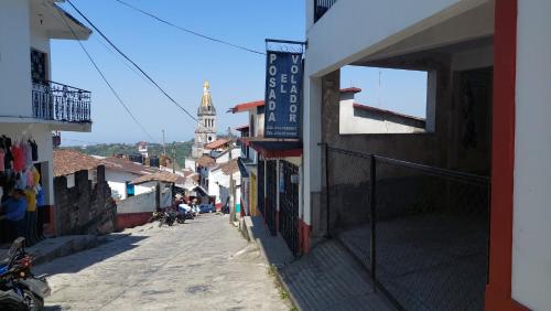 een smalle straat met een gebouw en een kerk bij Posada El Volador in Cuetzalán del Progreso