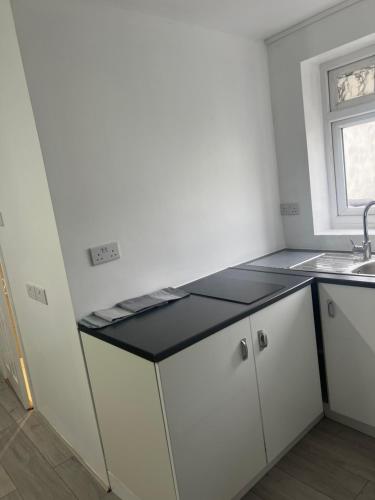 a kitchen with white cabinets and a black counter top at Montreal House in Barkingside