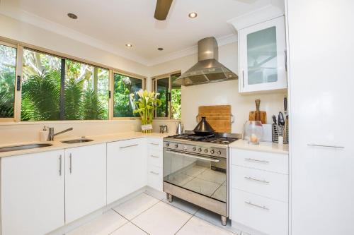 a kitchen with white cabinets and a stove at Eeast on Picnic in Picnic Bay