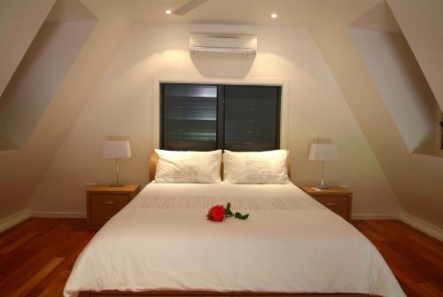 a bedroom with a white bed with a flower on it at Canopy Chalet 4 in Nelly Bay