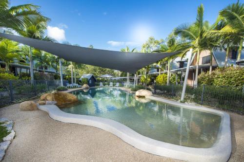 a swimming pool with an umbrella in front of a building at Canopy Chalet 4 in Nelly Bay