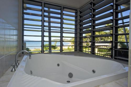 a bath tub in a bathroom with a large window at Magnetic Docks Townhouse 9 in Nelly Bay