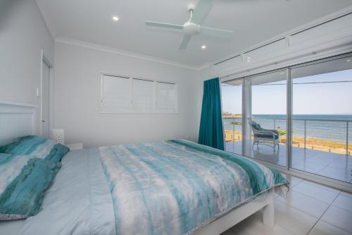 a bedroom with a bed and a view of the ocean at Sandy Decks in Nelly Bay