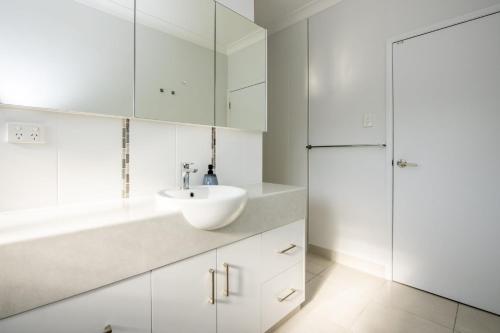 a white bathroom with a sink and a refrigerator at Sandy Decks in Nelly Bay