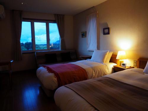 a hotel room with two beds and a window at Hillside Inn Sirocco in Tateyama
