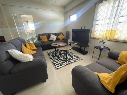 a living room with couches and a flat screen tv at Mango Vert House in Arima