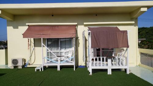 zwei Stühle auf der Veranda eines Hauses in der Unterkunft 宮古島ゲストハウス　マウイ in Arazato