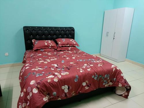 ein rotes Bett mit einer roten Bettdecke und Kissen in der Unterkunft MJ homestay in Nibung Tebal