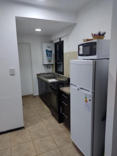W kuchni znajduje się biała lodówka i kuchenka mikrofalowa. w obiekcie Dpto temporal Azhares Juan Bautista ALBERDI 187 Octavo piso B w mieście San Salvador de Jujuy