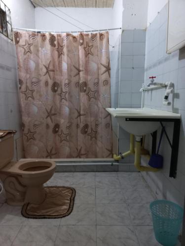 a bathroom with a shower curtain and a toilet and a sink at Casa de los Cruz in Leticia