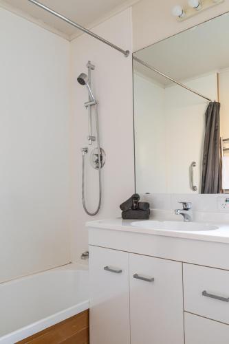 a white bathroom with a shower and a sink at Turner Heights Townhouses in Queenstown