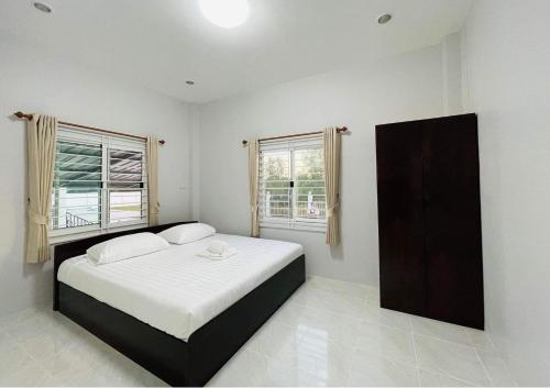 a bedroom with a bed and two windows at PPN Garden Resort in Suwannaphum