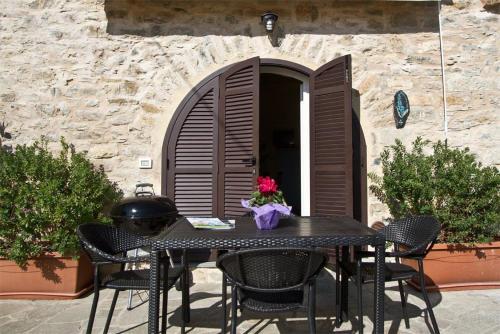 a table with chairs and a vase of flowers on a patio at Appartamenti Chiarina in Dolcedo
