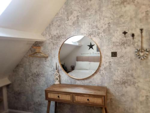 1 dormitorio con espejo redondo y cama en Cosy Moat House Cottage #3, en Pembroke