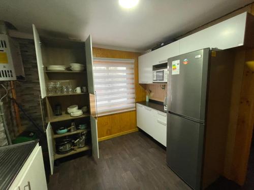 a kitchen with a stainless steel refrigerator and wooden floors at Casa en Puerto Natales in Puerto Natales