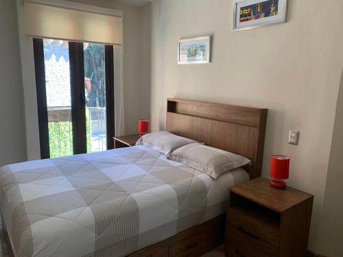 1 dormitorio con 1 cama y una ventana con 2 velas rojas en Loft Bonanza Premier en Valquirico, en Tlaxcala de Xicohténcatl