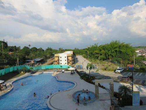 a pool at a resort with people in it at Alojamiento con piscina en el eje cafetero in La Tebaida