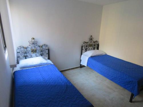 two beds in a room with blue sheets at Alojamiento con piscina en el eje cafetero in La Tebaida