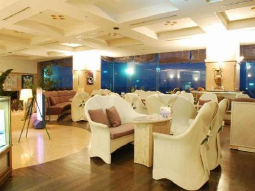 un salón con sillas blancas y una sala de espera en Hotel Cetus Royal, en Higashiizu