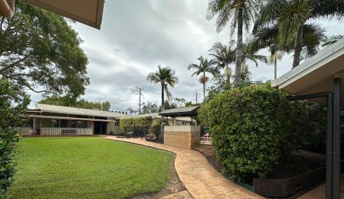 a house with a lawn and palm trees at Mareeba Motor Inn in Mareeba