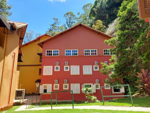 a red building with white windows on a mountain at Hotel Vila Suíça 1818 in Nova Friburgo