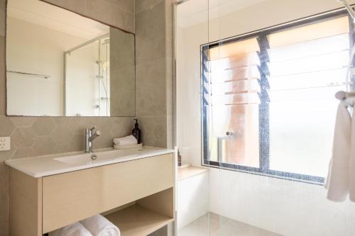 a bathroom with a sink and a mirror and a shower at Cavvanbah Beach Villa in Byron Bay