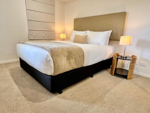 - une chambre dotée d'un grand lit avec des draps et des oreillers blancs dans l'établissement Sixty Six Boutique Apartments, à Hobart