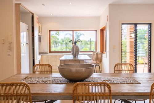a dining room with a large wooden table with chairs at Cavvanbah Beach Villa in Byron Bay