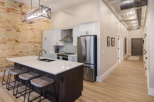 a kitchen with white cabinets and a large island with bar stools at Golden Lofts Unit 4 Downtown Traverse City 2BD 2BA in Traverse City