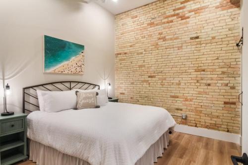 a bedroom with a brick wall and a bed at Golden Lofts Unit 4 Downtown Traverse City 2BD 2BA in Traverse City