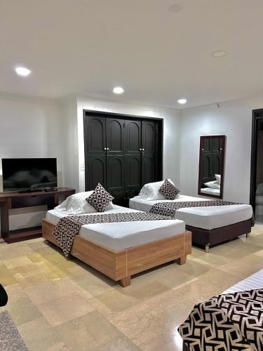 a bedroom with two beds and a television in it at Hotel Ingenio Reina Isabel in Cali