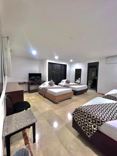 a hotel room with two beds and a television at Hotel Ingenio Reina Isabel in Cali