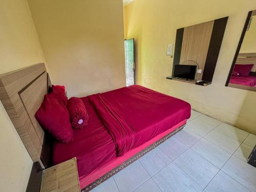 a red bed in a room with a television at Greenville Hotel Mitra RedDoorz in Sampit