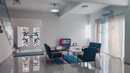 Gopeng Serumah Holiday House في Gopeng: غرفة معيشة فيها كراسي وطاولة وتلفزيون