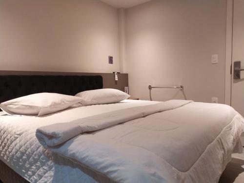 a large bed with white sheets and pillows at Hotel Vila Suíça 1818 in Nova Friburgo