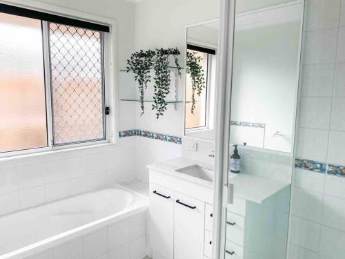 a white bathroom with a tub and a sink at Perfect Noosa Pad with Pool in Noosaville