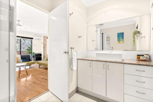 a white bathroom with a sink and a mirror at Back Beach Beauty in Smiths Beach