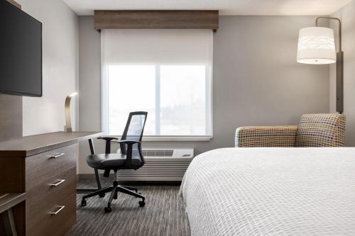 a hotel room with a bed and a chair and a window at Holiday Inn Express Hotel & Suites Anniston/Oxford by IHG in Oxford