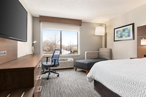 a hotel room with a bed and a desk and a chair at Holiday Inn Express Hotel & Suites Anniston/Oxford by IHG in Oxford