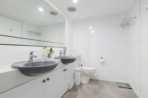 Baño blanco con 2 lavabos y aseo en Suite 305 Sandcastles 3 Bedroom Deluxe Apartment, en Perth